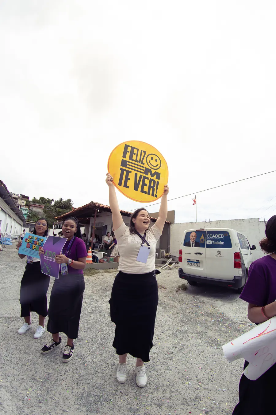 Volunt&aacute;ria levantando uma placa com a frase Feliz em te ver na recep&ccedil;&atilde;o do congresso